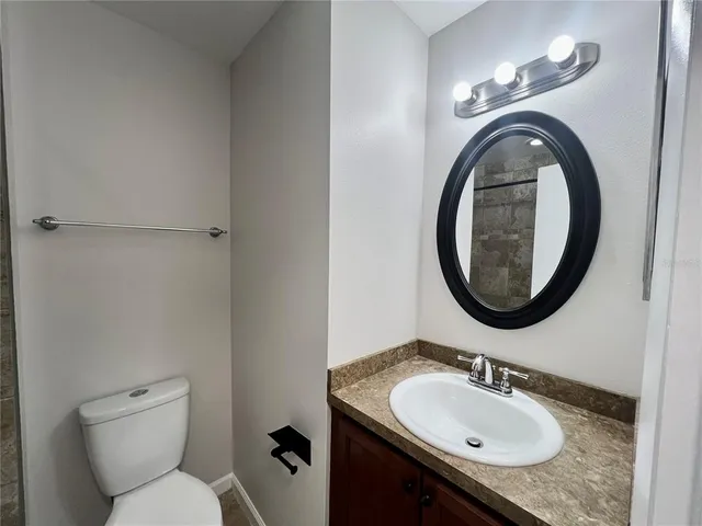 a bathroom with a granite countertop toilet a sink and a mirror