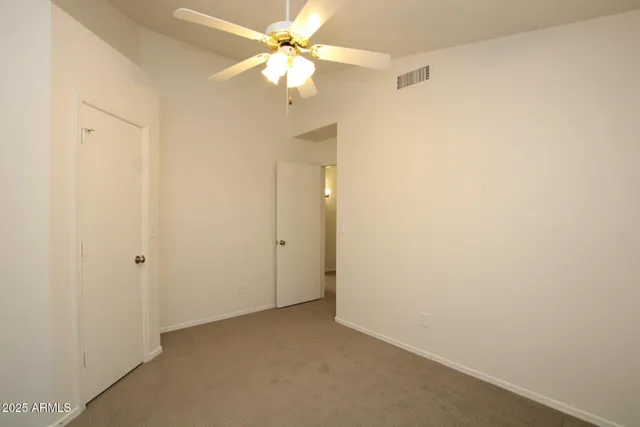 an empty room with a ceiling fan and a window