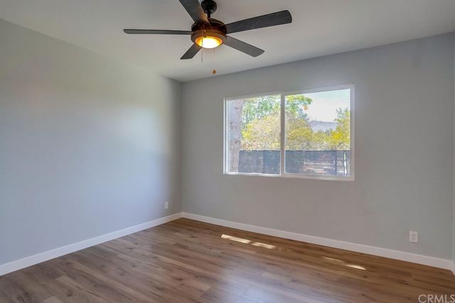 a view of an empty room with wooden floor and window