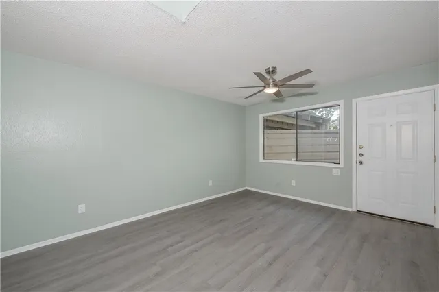 a view of an empty room with a ceiling fan and wooden floor