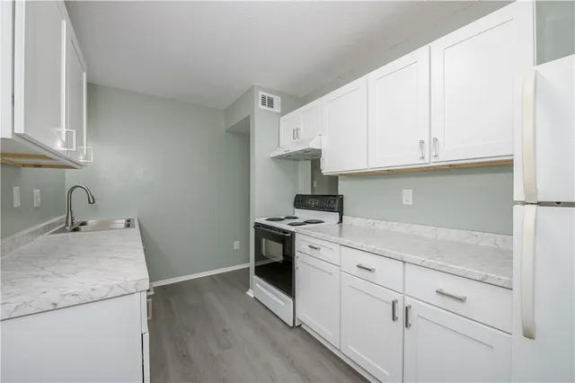 a kitchen with granite countertop white cabinets and white appliances