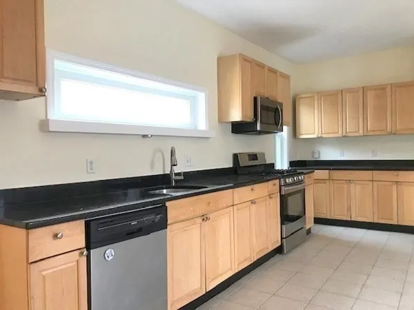 a kitchen with granite countertop white cabinets sink and stainless steel appliances