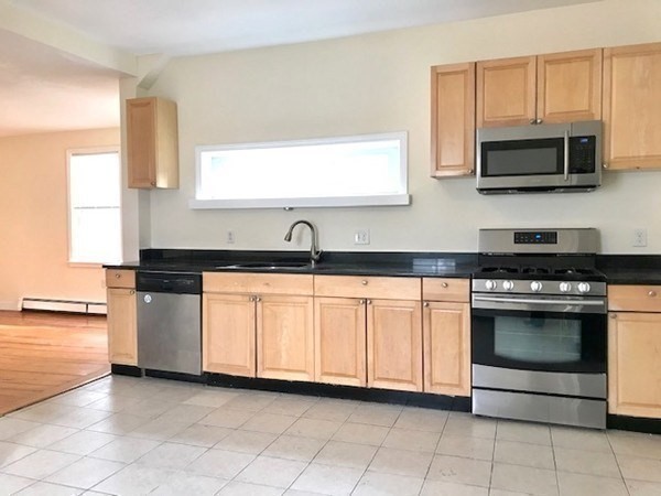 22 Marcella Street, Unit 2 Boston, MA 02119 - Photo 5 of 12 a kitchen with stainless steel appliances granite countertop white cabinets a microwave oven and a sink