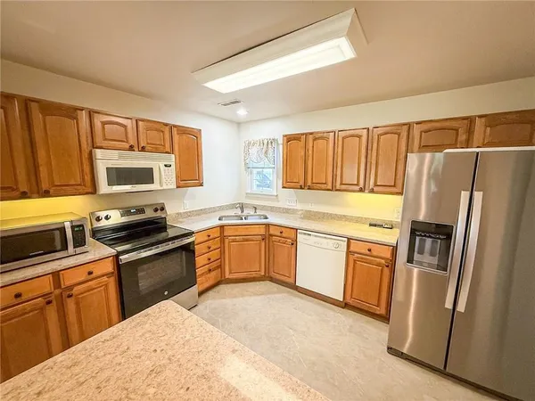 a kitchen with granite countertop a refrigerator stove top oven and sink