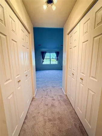 a view of a hallway with wooden door and a window