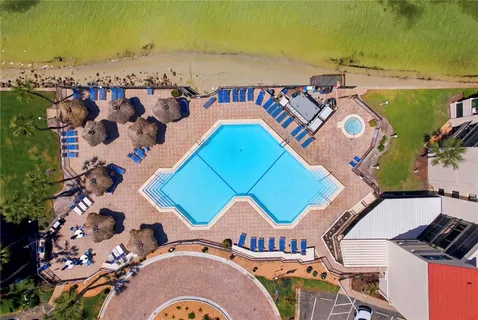 an aerial view of a swimming pool a playground lake and mountain view in back