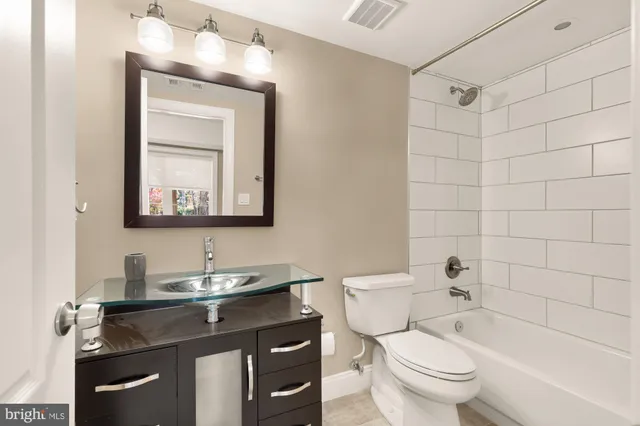 a bathroom with a granite countertop toilet a sink and a mirror