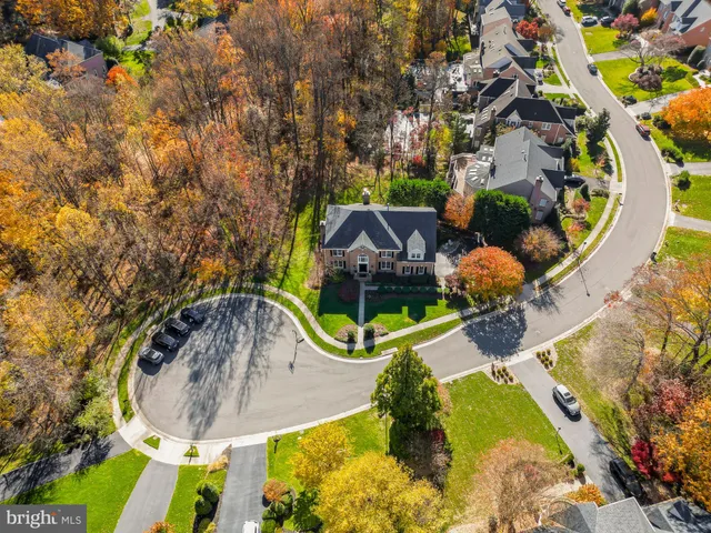 an aerial view of a house with swimming pool and large trees