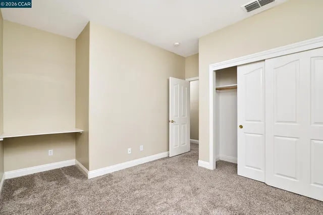 a view of an empty room with chandelier fan and fire place