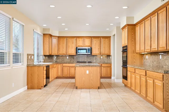 a large kitchen with stainless steel appliances granite countertop a refrigerator and a sink