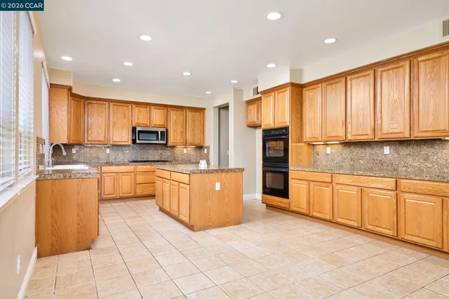 a large kitchen with stainless steel appliances granite countertop a stove top oven a sink dishwasher and cabinets with granite countertops