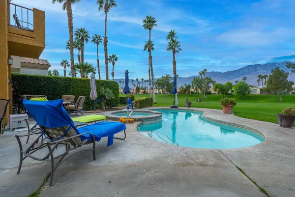 a view of a swimming pool with lawn chairs and a yard