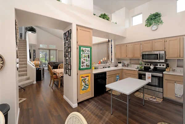 a kitchen with a refrigerator a stove top oven a sink dishwasher and white cabinets with wooden floor