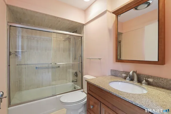 a bathroom with a granite countertop sink toilet and shower