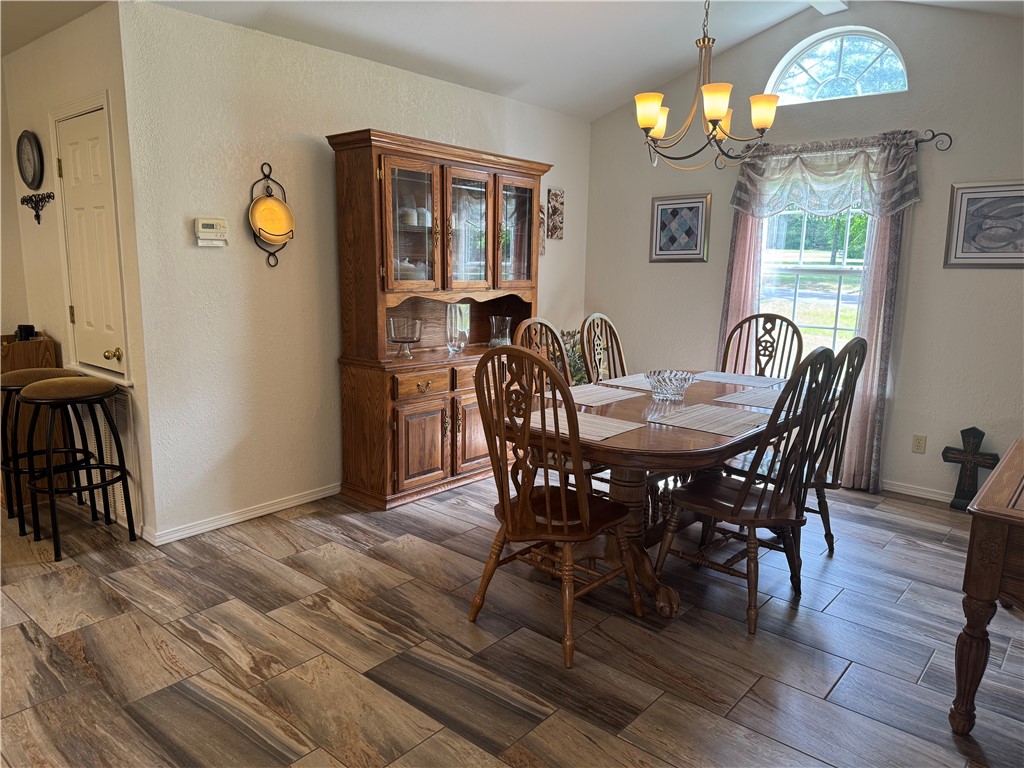 95 Deer Run Road Delaware, AR 72835 - Photo 23 of 40 Vaulted ceiling featuring an arched window, wood-finish flooring, and a multi-light chandelier