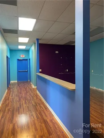 a view of an empty room with a kitchen and a window