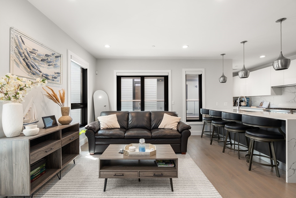 39 A Street, Unit 16 Boston, MA 02127 - Photo 1 of 14 a living room with furniture and a dining table with wooden floor