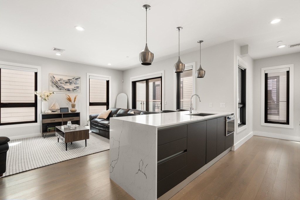 39 A Street, Unit 16 Boston, MA 02127 - Photo 4 of 14 a large kitchen with kitchen island a large counter top space a sink a stove and wooden floor
