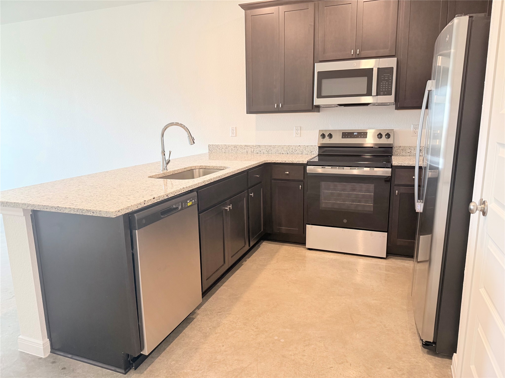 2909 Quail Rdg Lane, Unit A Temple, TX 76501 - Photo 4 of 19 Kitchen featuring stainless steel appliances, a peninsula, light stone counters, and dark wood finish cabinets