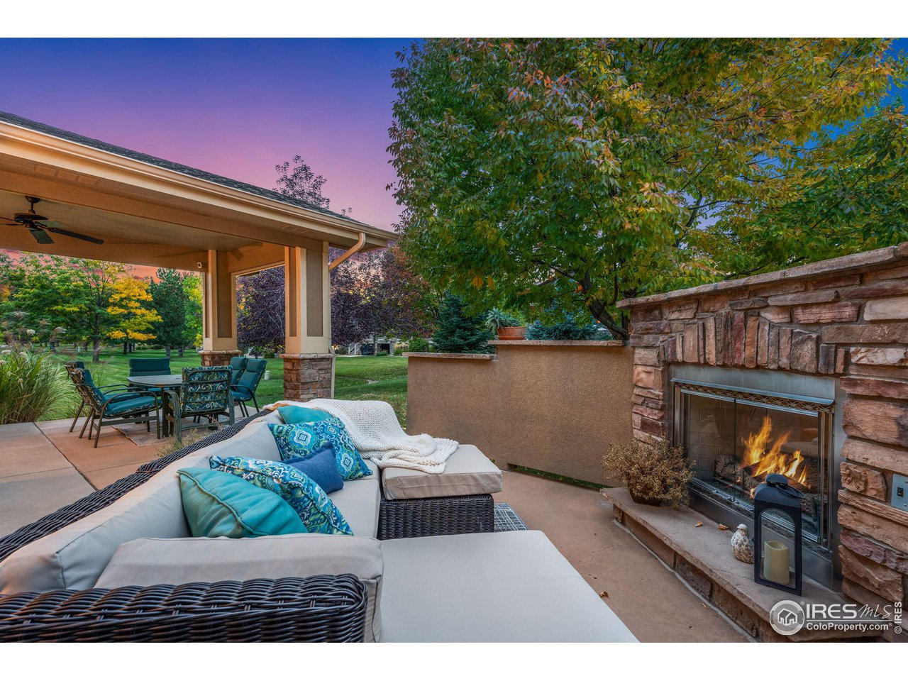 6511 Half Moon Bay Drive Windsor, CO 80550 - Photo 29 of 31 a view of a patio with couches table and chairs under an umbrella with a small yard