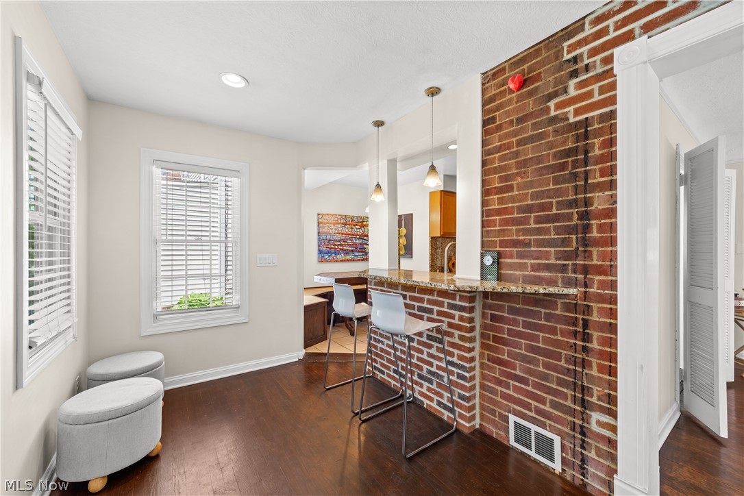 3806 Westwood Road University Heights, OH 44118 - Photo 10 of 41 Exposed brick accent wall with a granite countertop breakfast bar, complemented by recessed lighting and rich wood-finish flooring