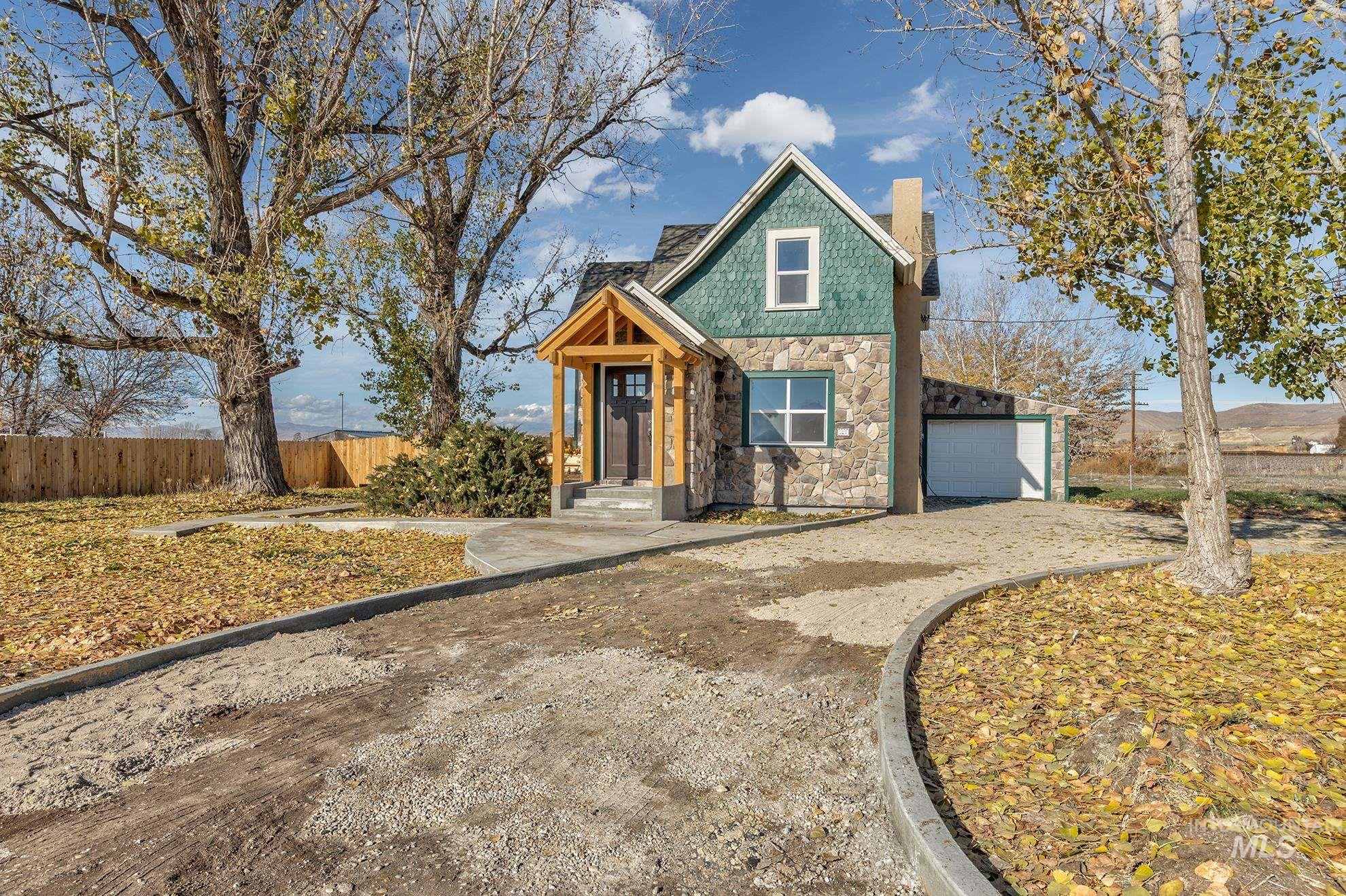 327 Macomb Road Weiser, ID 83672 - Photo 2 of 49 View of front of home with stone siding, a chimney, a garage, and driveway