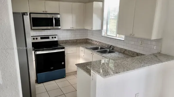 a kitchen with granite countertop a sink and a stove top oven