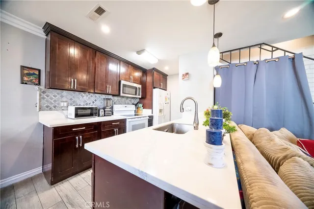 a kitchen with sink a refrigerator and chairs
