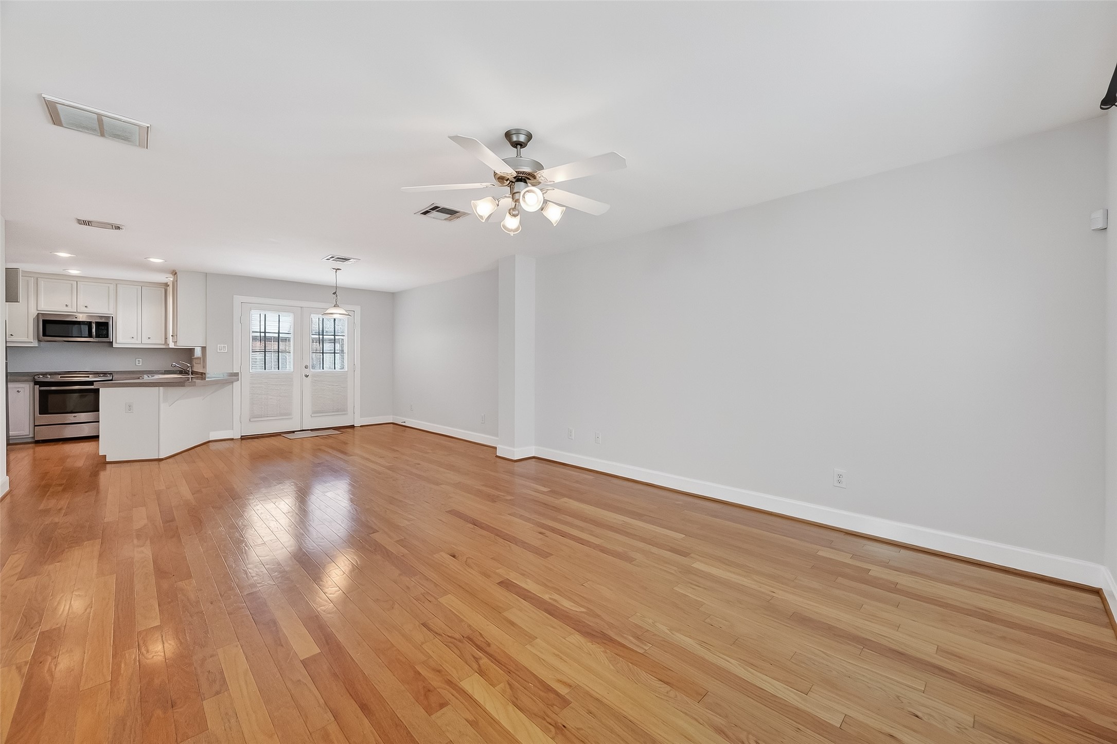 5951 S Loop East, Unit 47 Houston, TX 77033 - Photo 5 of 37 This open-concept living space features hardwood floors and ample natural light. The kitchen offers modern stainless steel appliances and white cabinetry. French doors lead to a large outdoor yard.