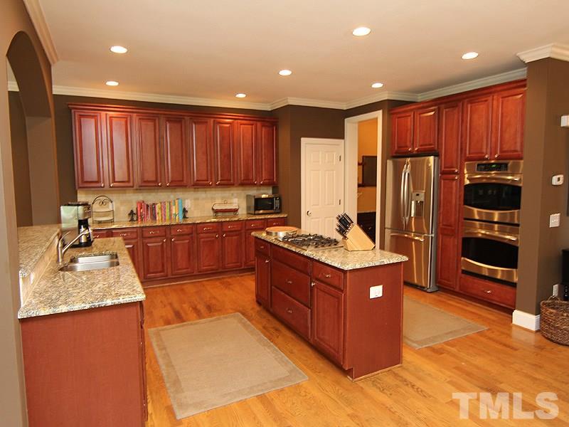 5041 Oak Park Road Raleigh, NC 27612 - Photo 8 of 19 a kitchen with stainless steel appliances granite countertop a stove top oven a refrigerator and a sink with wooden floor