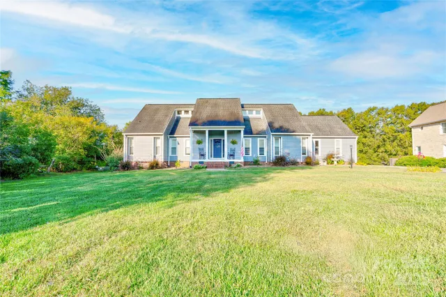 a front view of house with yard and trees in the background