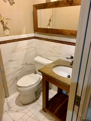 a bathroom with a granite countertop toilet sink and mirror