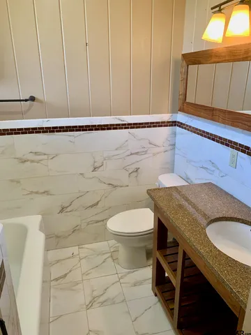 a bathroom with a granite countertop sink and a toilet