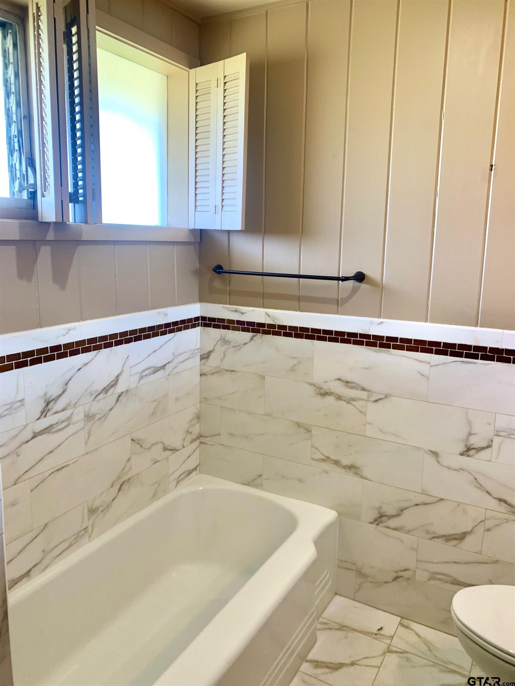 829 East Goode Street Quitman, TX 75783 - Photo 16 of 20 a bathroom with a bathtub and next to a window