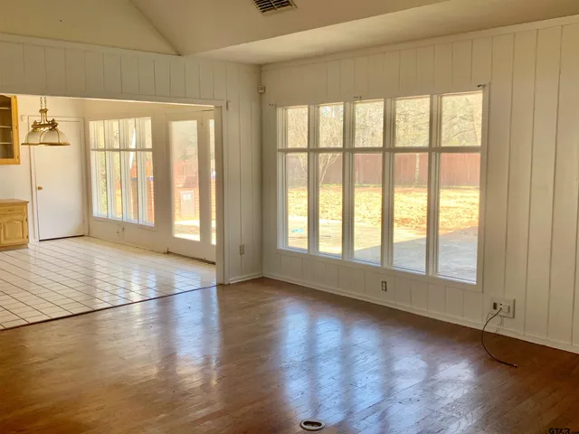 an empty room with wooden floor and windows