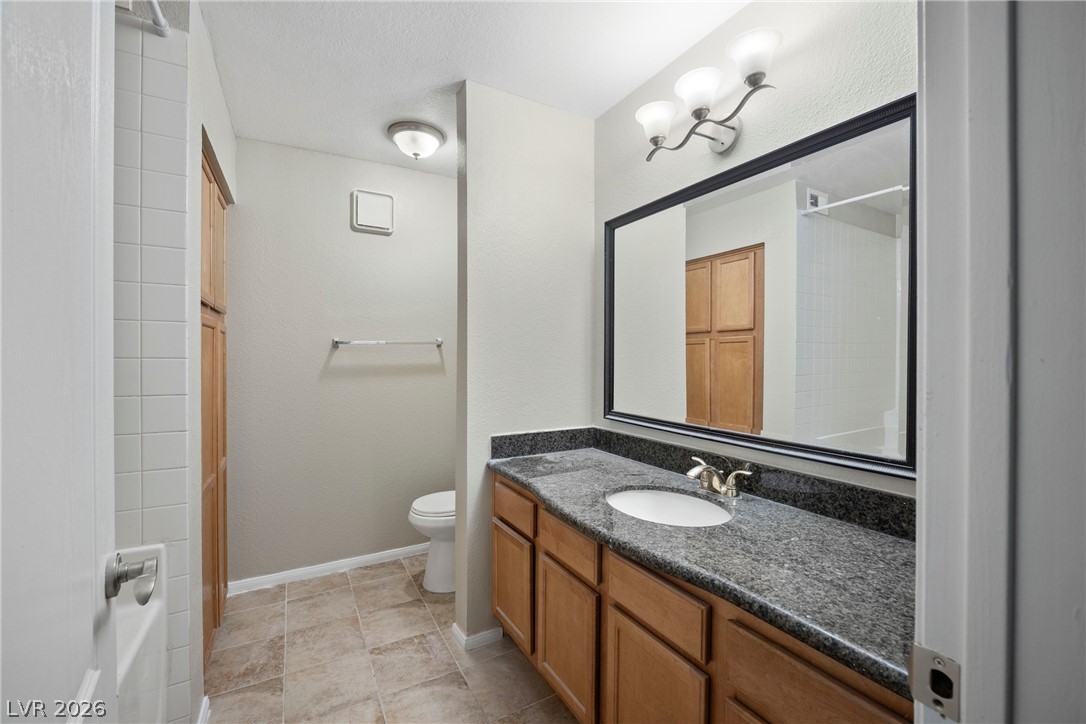 3145 East Flamingo Road, Unit 1055 Las Vegas, NV 89121 - Photo 28 of 40 A well-appointed bathroom features a single vanity with granite counters and rich wood cabinetry, offering practical storage.