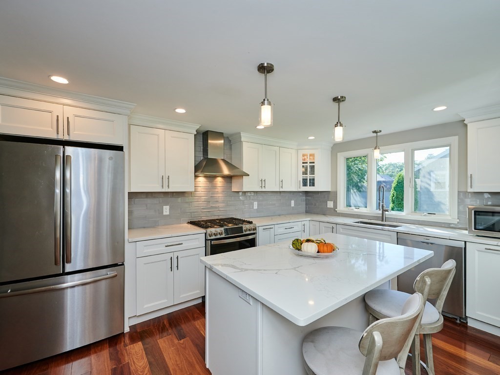 14 Hanson Street Wakefield, MA 01880 - Photo 11 of 32 a kitchen with stainless steel appliances a stove a sink a refrigerator wooden floor and white cabinets