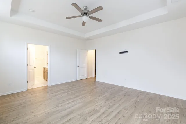an empty room with wooden floor and a ceiling fan