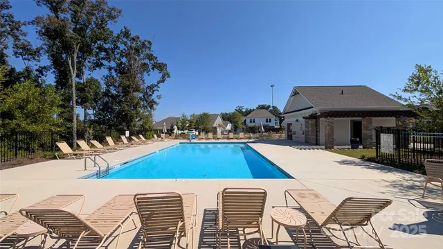 a view of swimming pool with outdoor seating and trees in the background