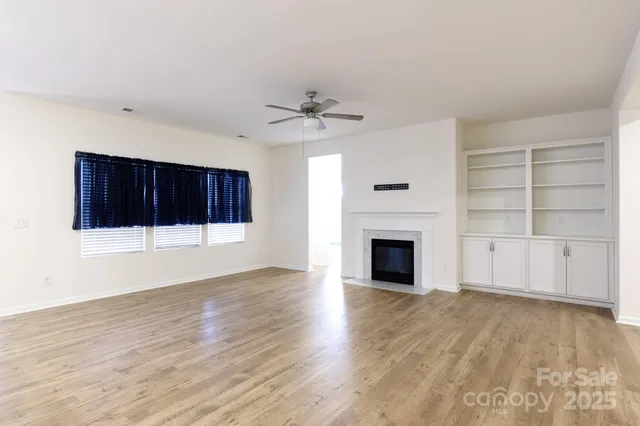 a view of a livingroom with a fireplace a ceiling fan and window