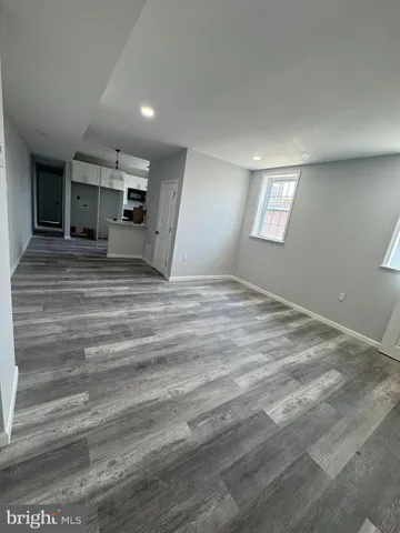 a view of empty room with kitchen and window