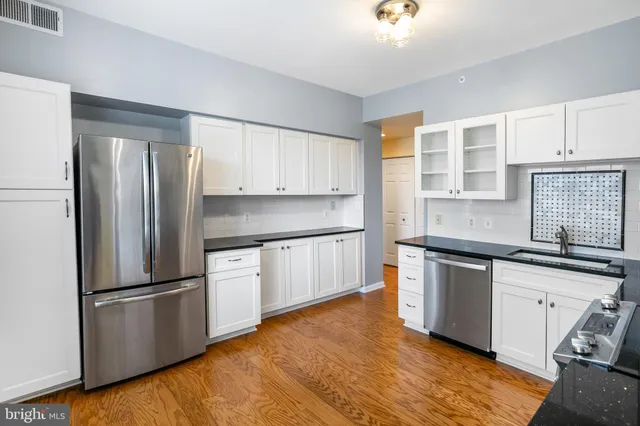 a kitchen with stainless steel appliances white cabinets and a stove top oven
