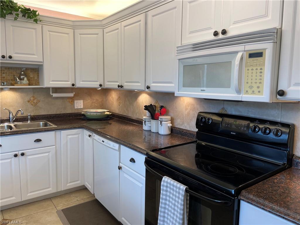 541 Teryl Road, Unit 1 Naples, FL 34112 - Photo 4 of 33 a kitchen with white cabinets a stove and a microwave