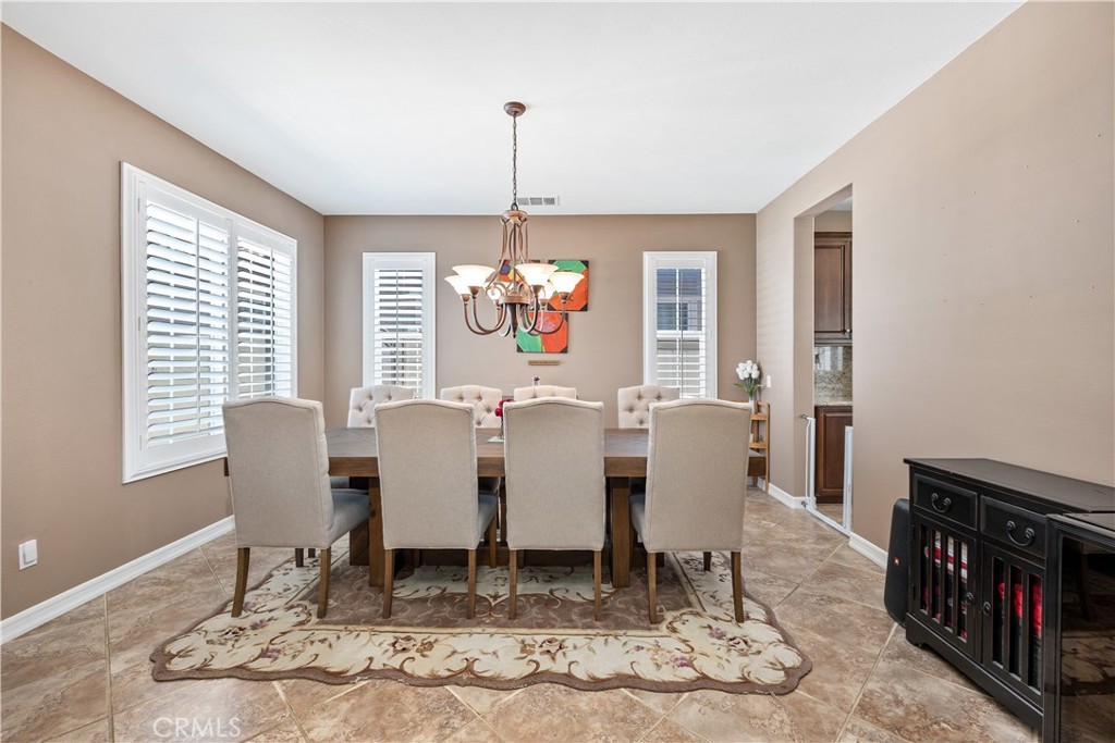 353 Caldera Street Perris, CA 92570 - Photo 15 of 53 a dining room with wooden floor a chandelier a wooden table and chairs
