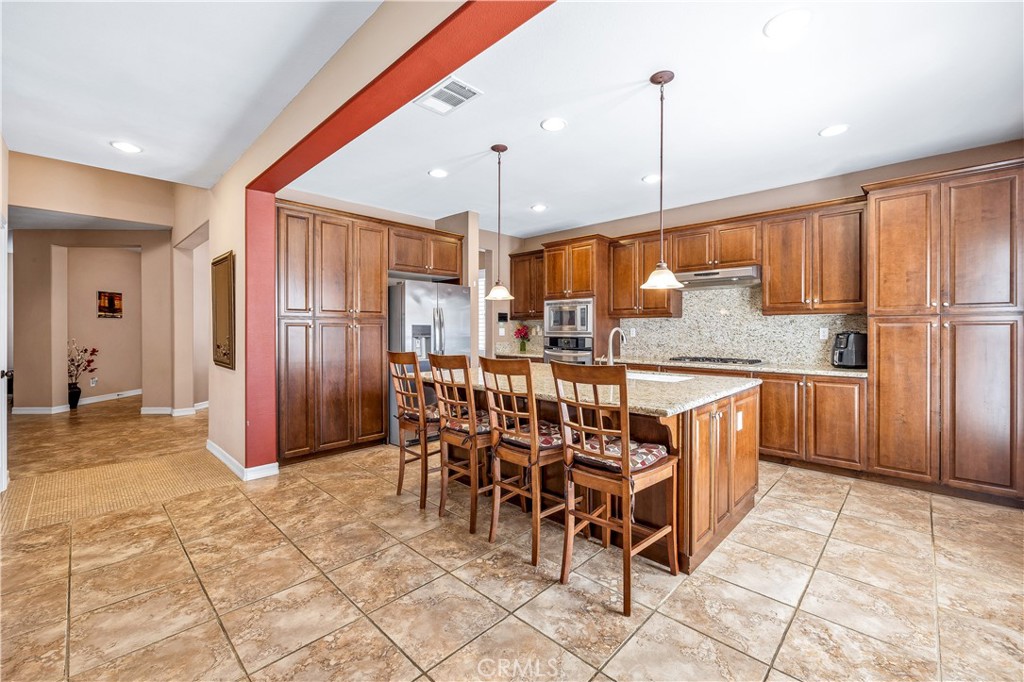 353 Caldera Street Perris, CA 92570 - Photo 19 of 53 a kitchen with stainless steel appliances kitchen island granite countertop a refrigerator and a sink