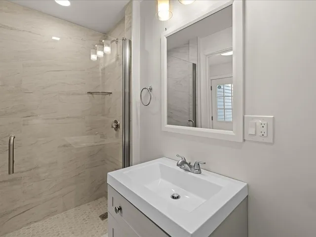 a bathroom with a sink mirror and shower