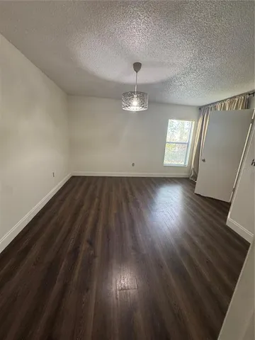 an empty room with wooden floor chandelier fan and windows
