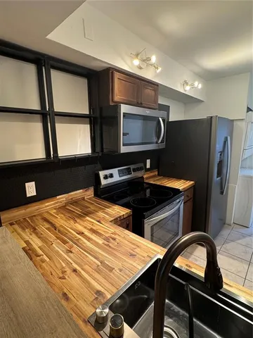 a kitchen with stainless steel appliances kitchen island granite countertop a refrigerator stove and microwave