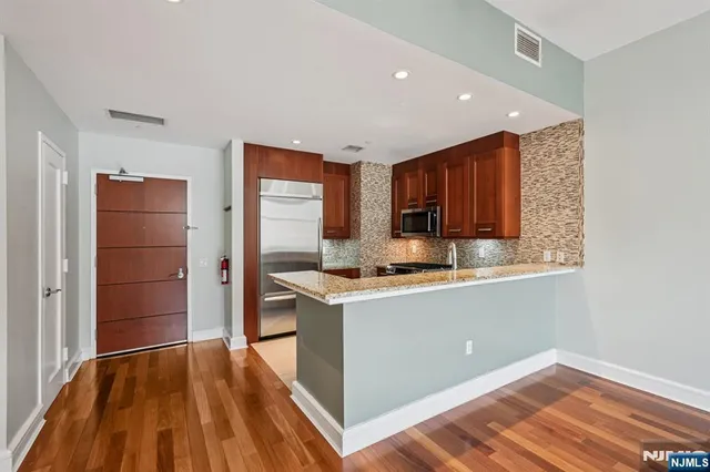 a kitchen with stainless steel appliances kitchen island granite countertop a refrigerator and a sink