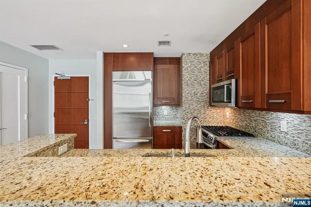 a kitchen with stainless steel appliances granite countertop a sink a stove and a wooden cabinets